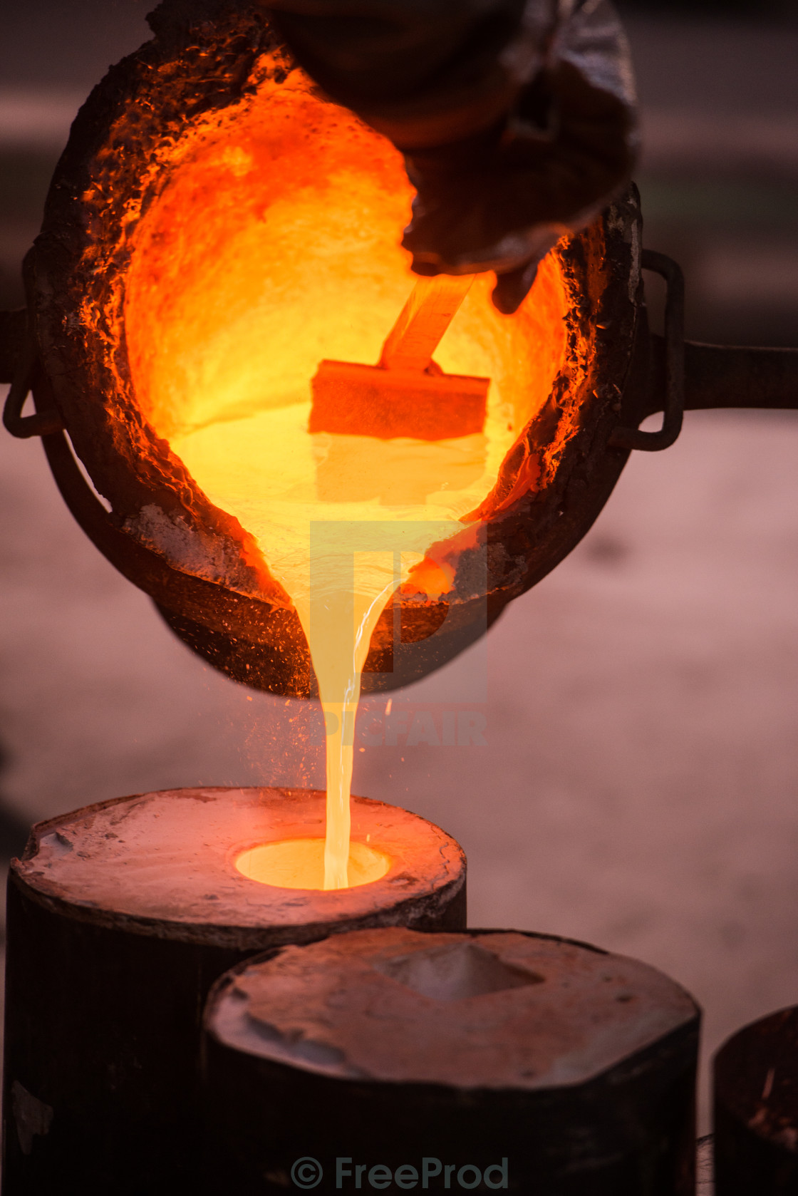 Foundry worker pouring hot metal into cast License, download or print